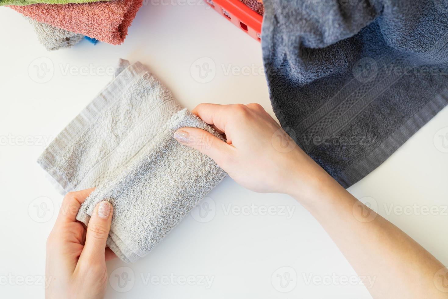 A woman's hand holds a terry towel from a clothes basket. Towel after washing. The girl folds the towel after washing, folding clothes. photo