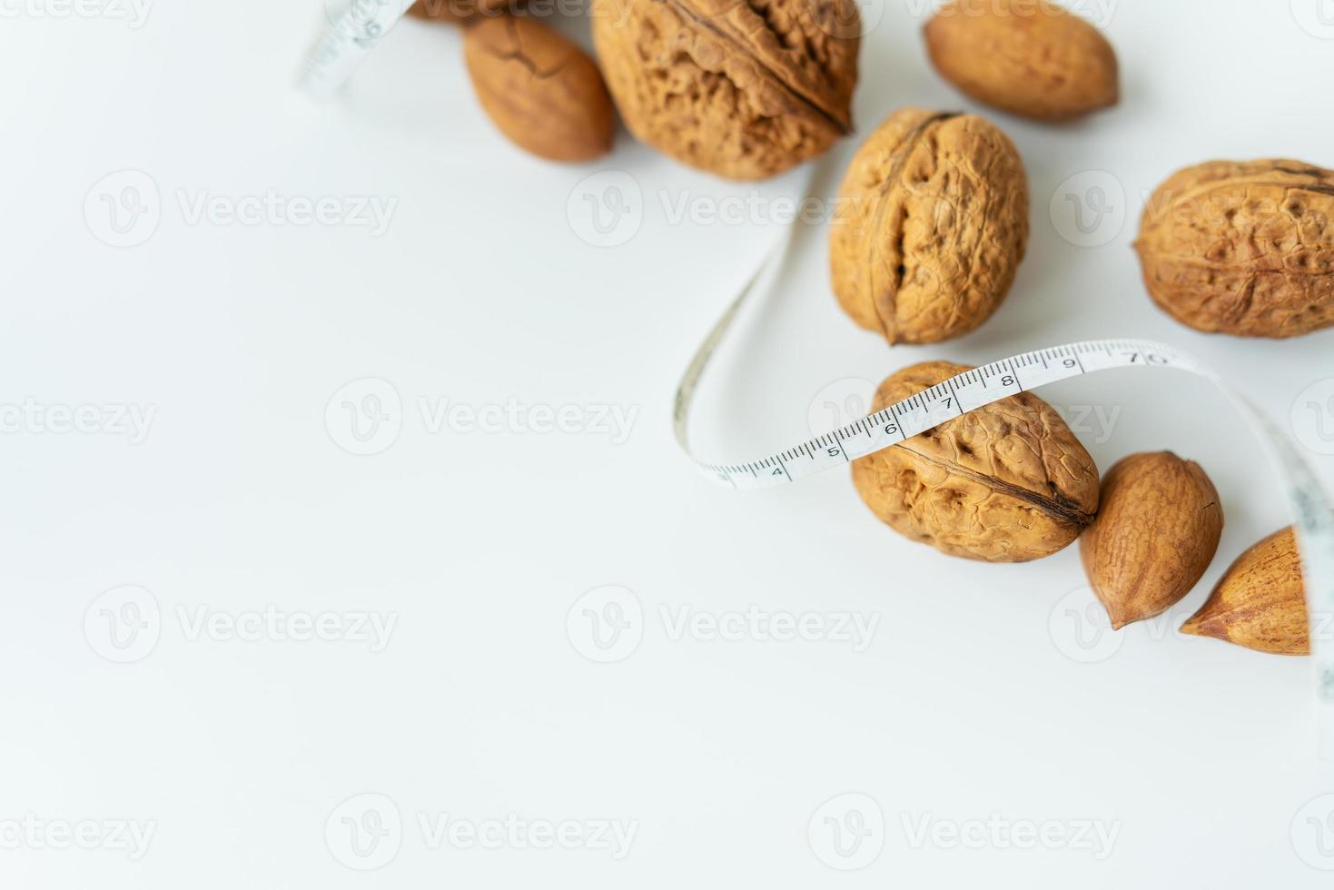 hermosos granos de nuez enteros yacen juntos con un pequeño centímetro, las nueces enteras en la cáscara se derraman sobre la mesa. enfoque selectivo, ruido. foto