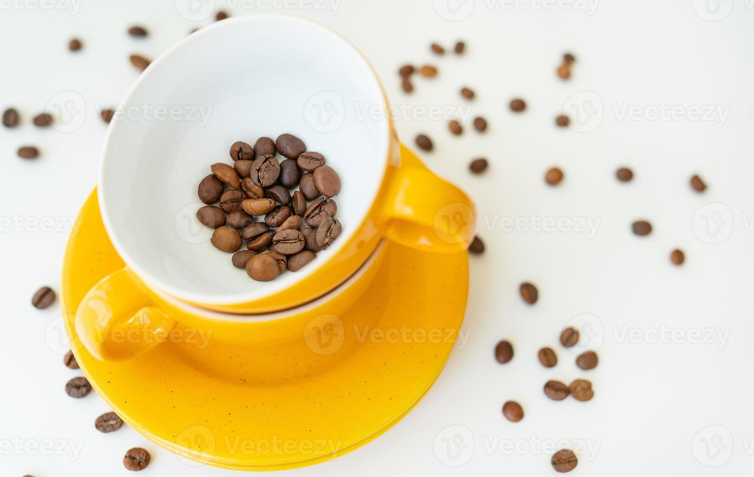 Beautiful morning, the process of making coffee, a yellow cup on a white table, scattered coffee beans. photo