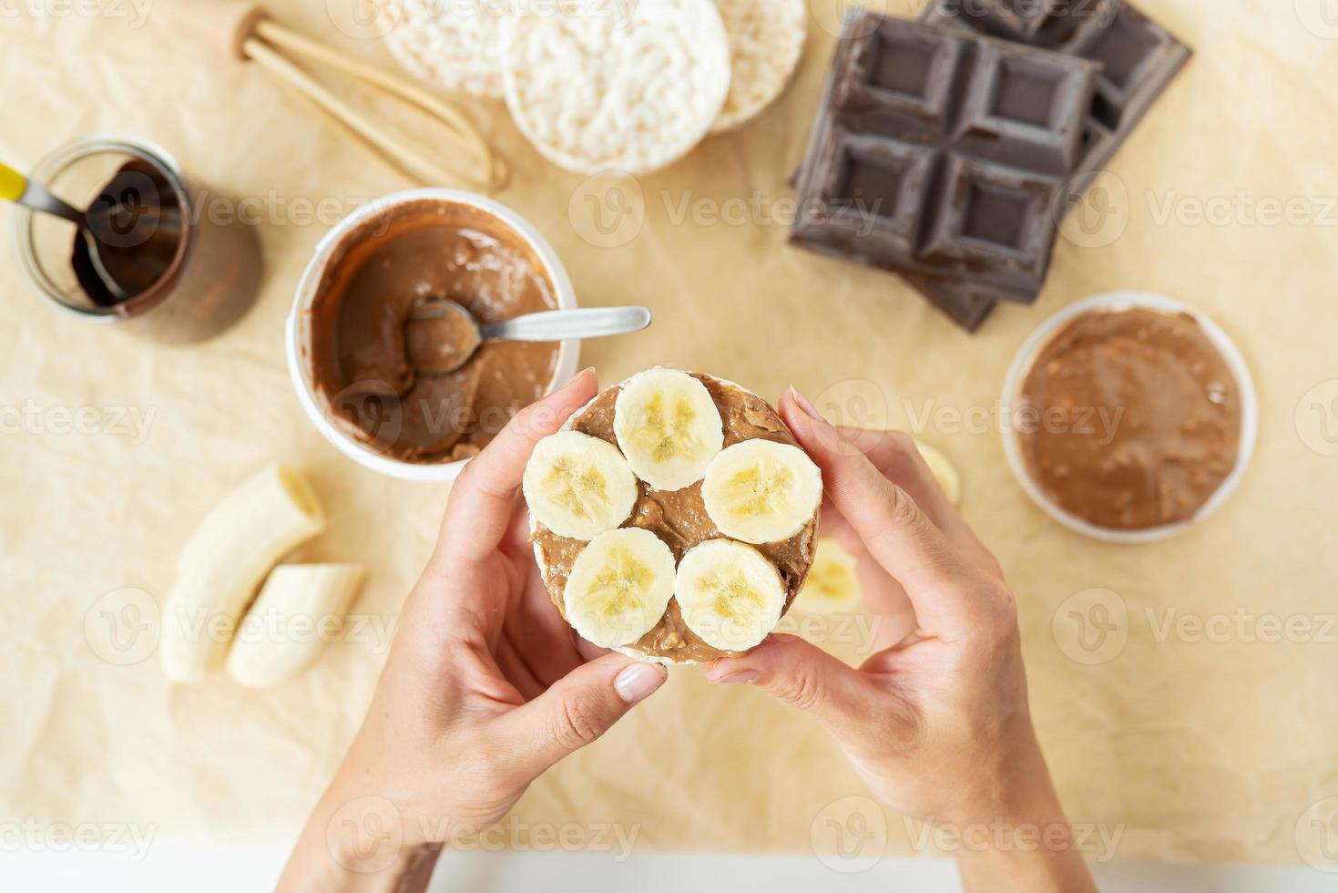 Top view of the process of preparing a delicious peanut butter dessert along with rice cakes and a banana. Vegan dessert, tasty and healthy. photo