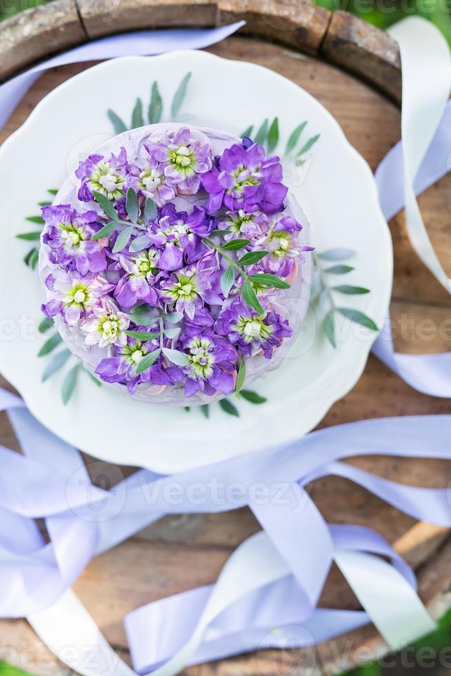Very beautiful bento cake with purple, veri peri, matthiola flowers with green leaves, top view. Birthday, beautiful ribbons. photo