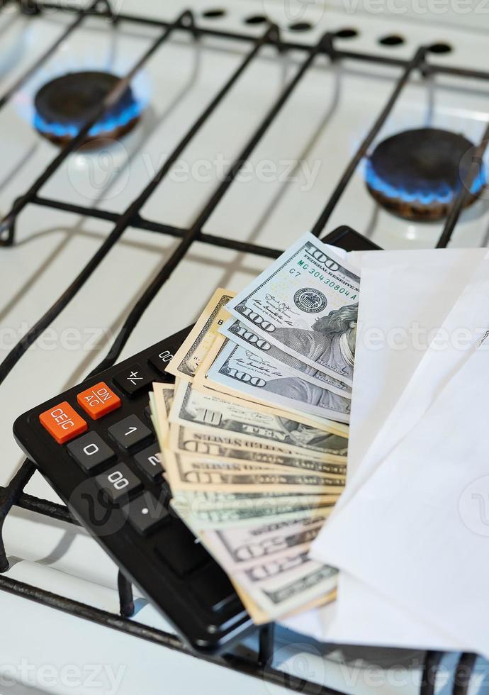 Payment of utility bills, calculations on a calculator. Euro and dollar bills lie near a burning gas burner. The concept of increasing the cost of natural gas supply and payment. Energy crisis photo