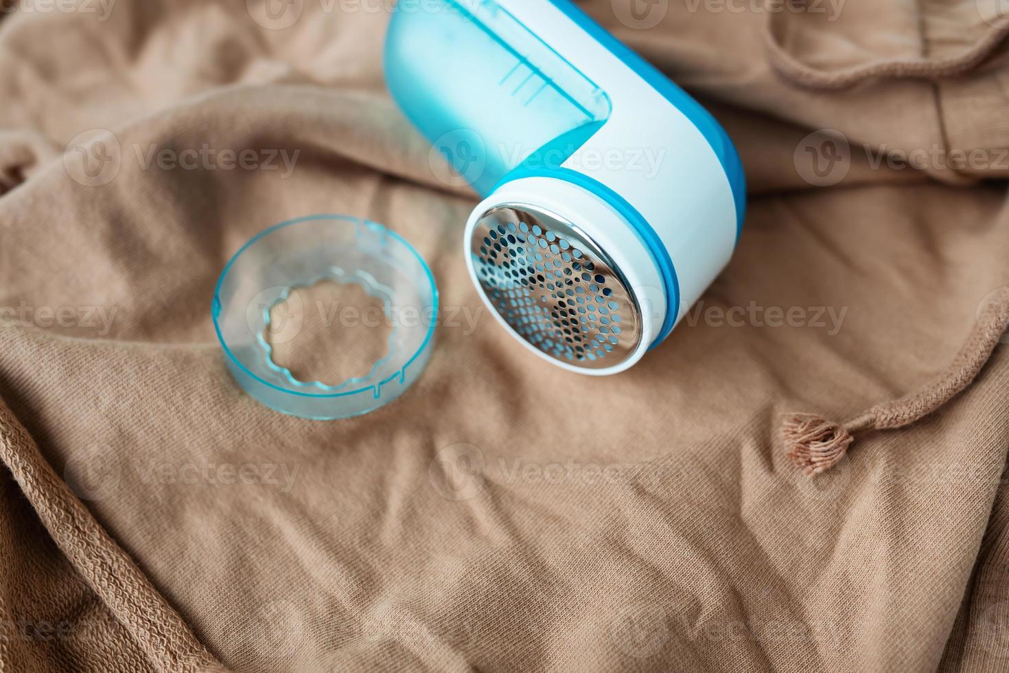 A girl removes large coils from clothes using an electronic machine. The concept of saving clothes, cleaning from coils. photo