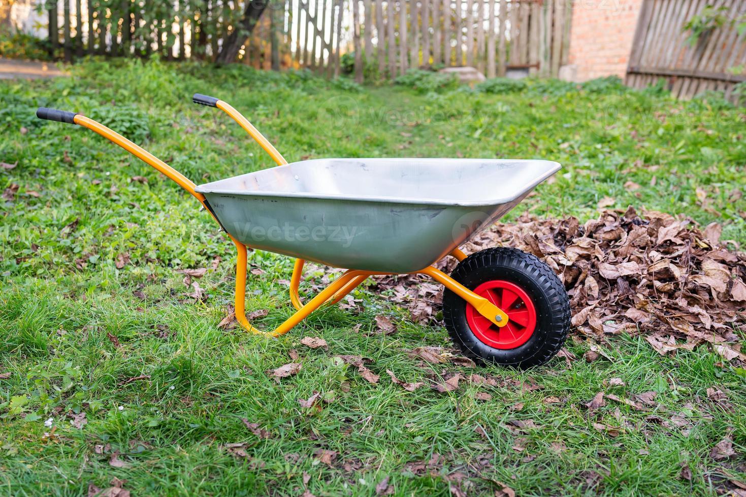 Metal wheelbarrow for trash, garbage, dry leaves. Collection of garbage or harvest in the country. photo