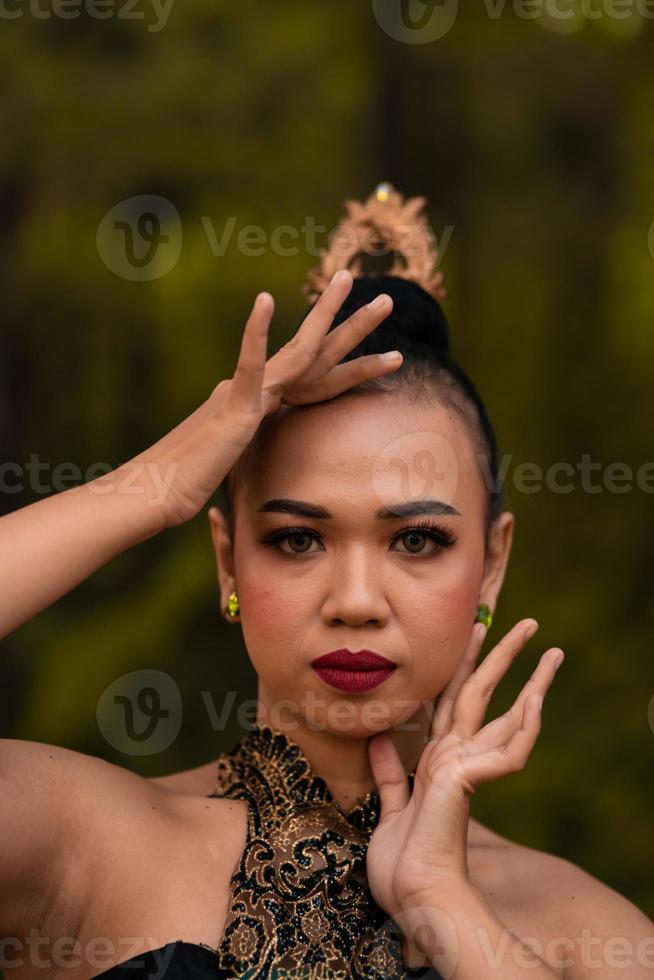 Brave Face of an Asian woman in a traditional green costume with golden accessories on her body during the competition in a dance festival photo