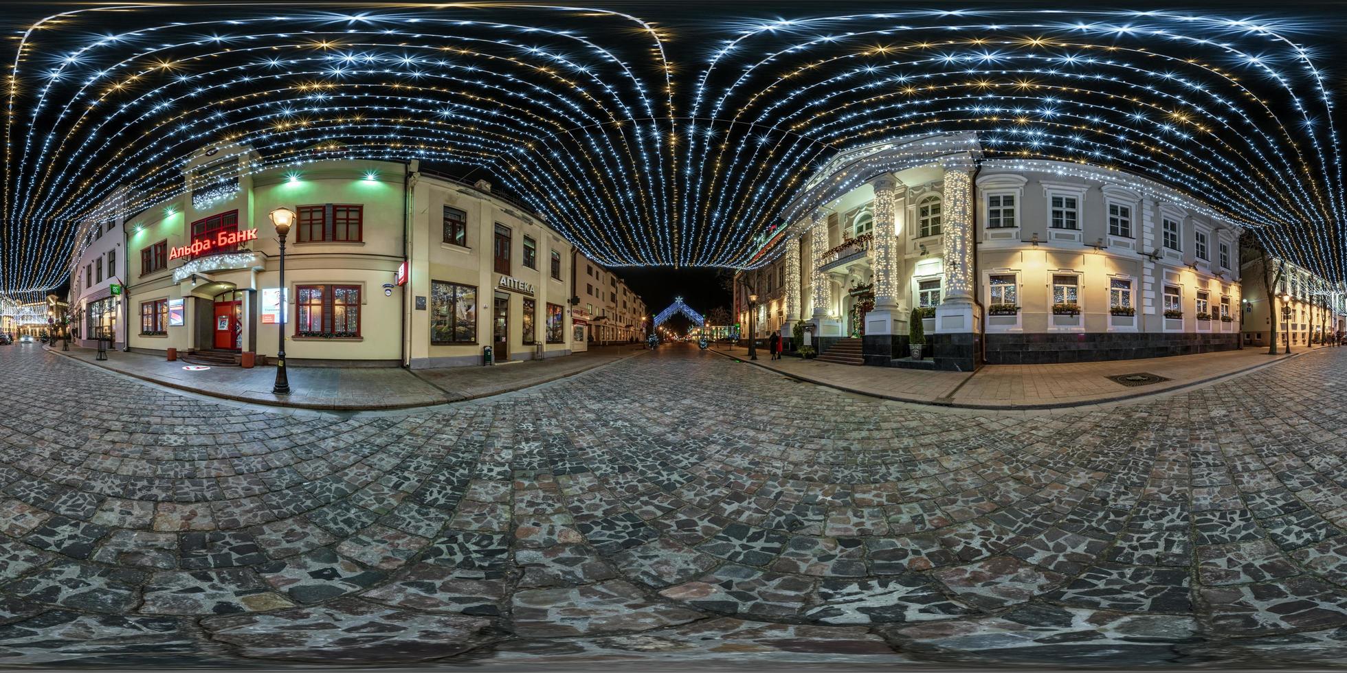 panorama esférico de noche transparente hdr 360 en calle peatonal con pavimento de piedra del casco antiguo con decoración festiva e iluminaciones en proyección equirectangular foto