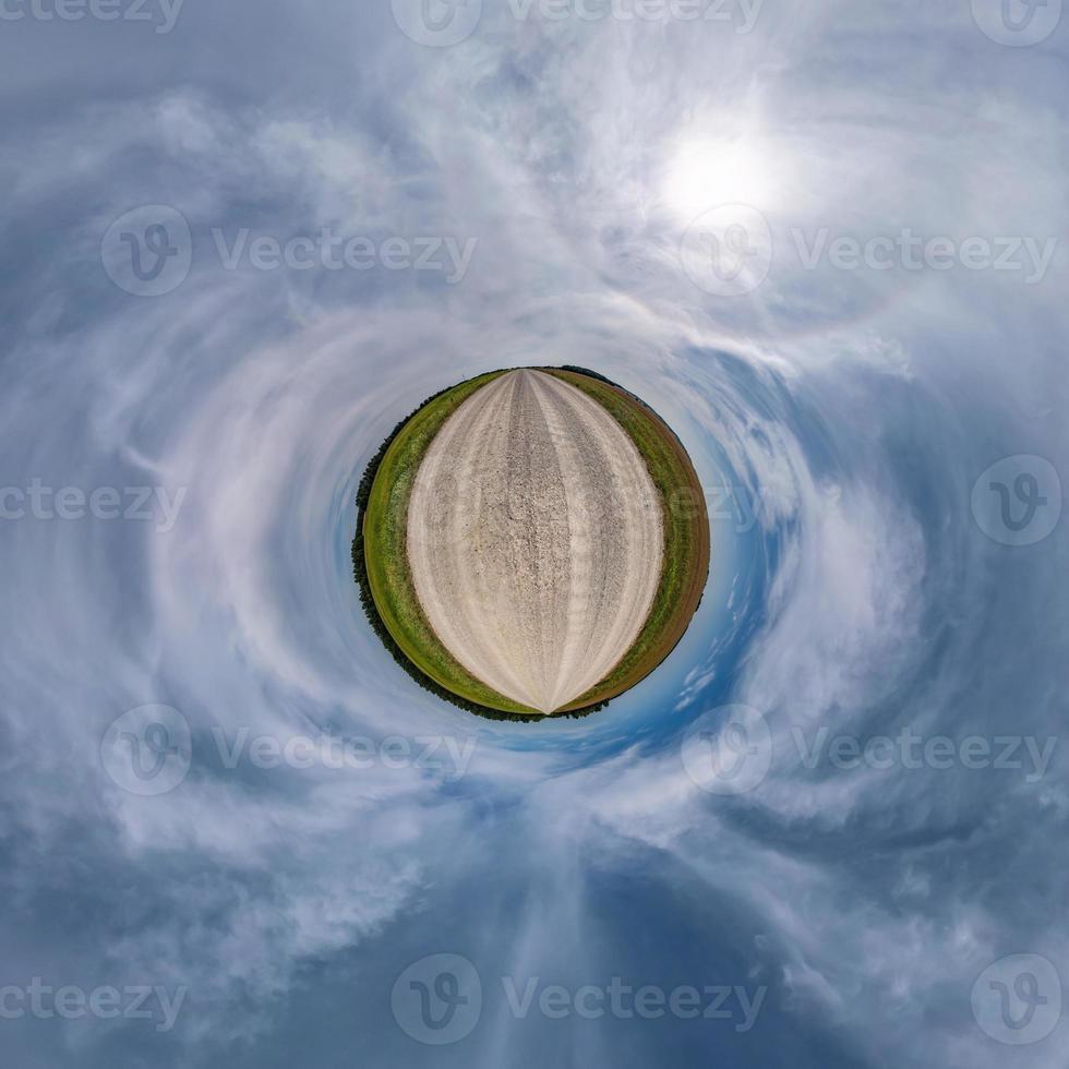 tiny planet in blue overcast sky with beautiful clouds with transformation of spherical panorama 360 degrees. Spherical abstract aerial view. Curvature of space. photo