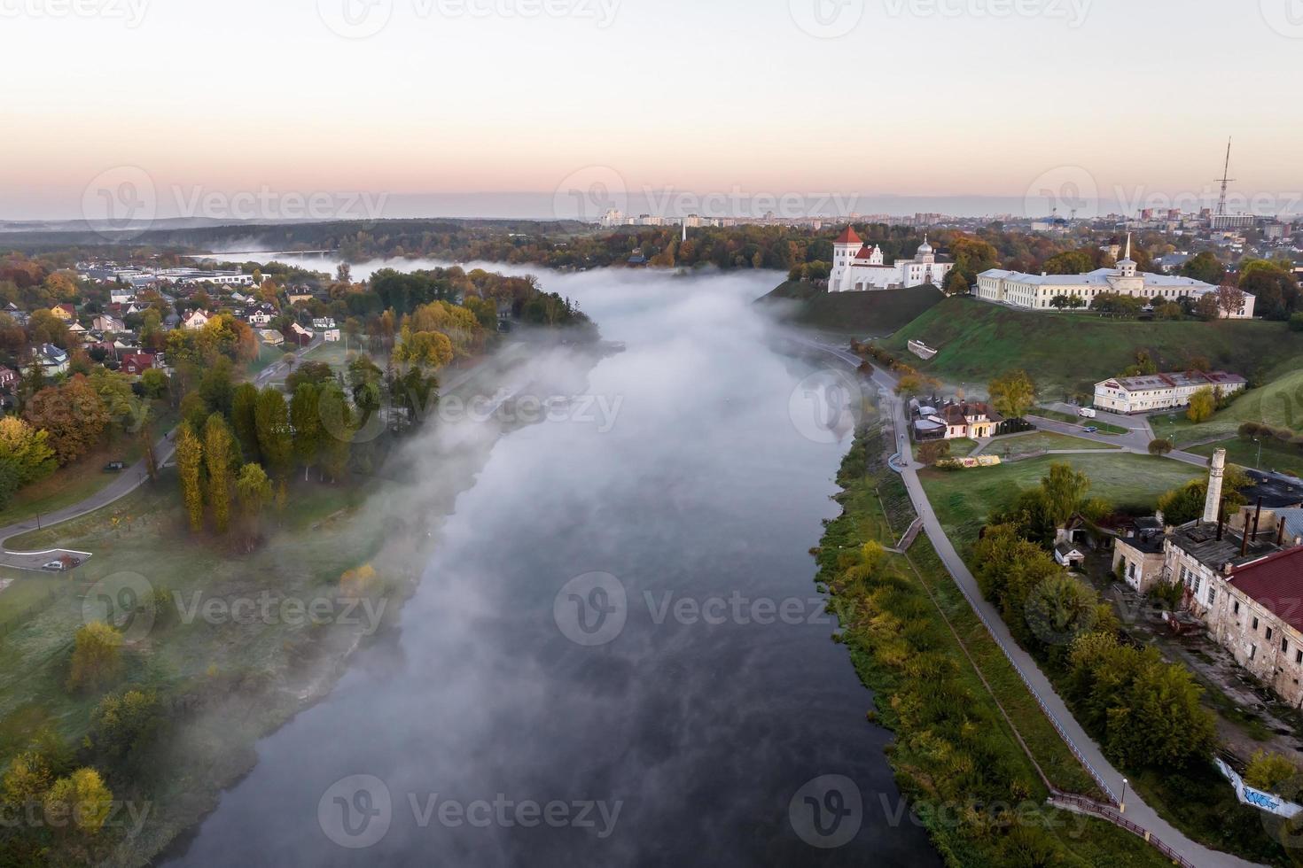 earlier foggy morning and aerial panoramic view on medieval castle and promenade overlooking the old city and historic buildings near wide river with bridge photo