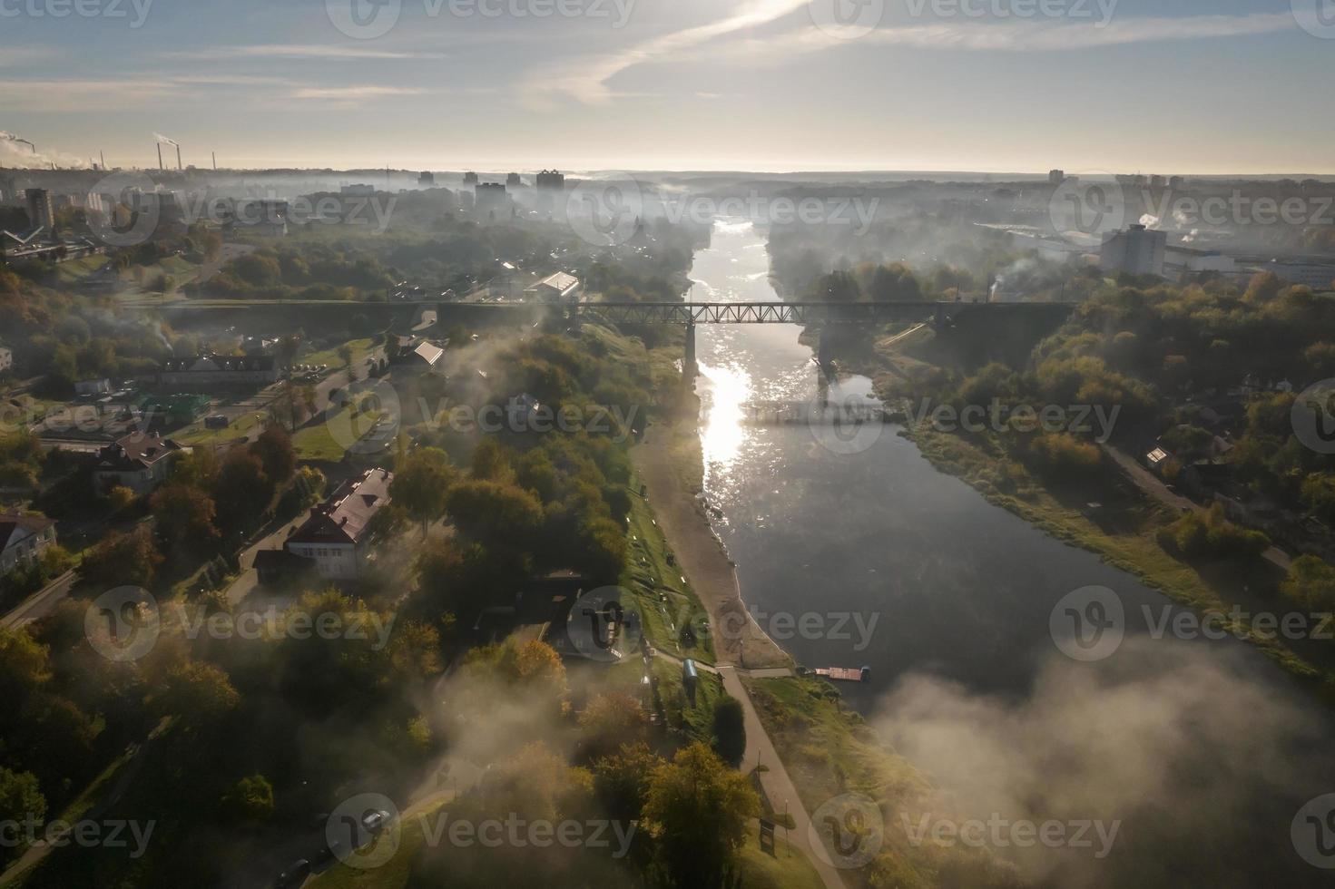 earlier foggy morning and aerial panoramic view on medieval castle and promenade overlooking the old city and historic buildings near wide river with bridge photo
