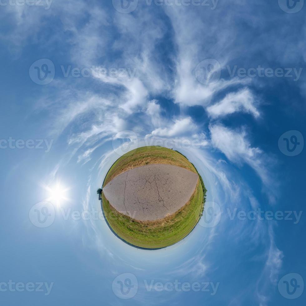 tiny planet in blue overcast sky with beautiful clouds with transformation of spherical panorama 360 degrees. Spherical abstract aerial view. Curvature of space. photo
