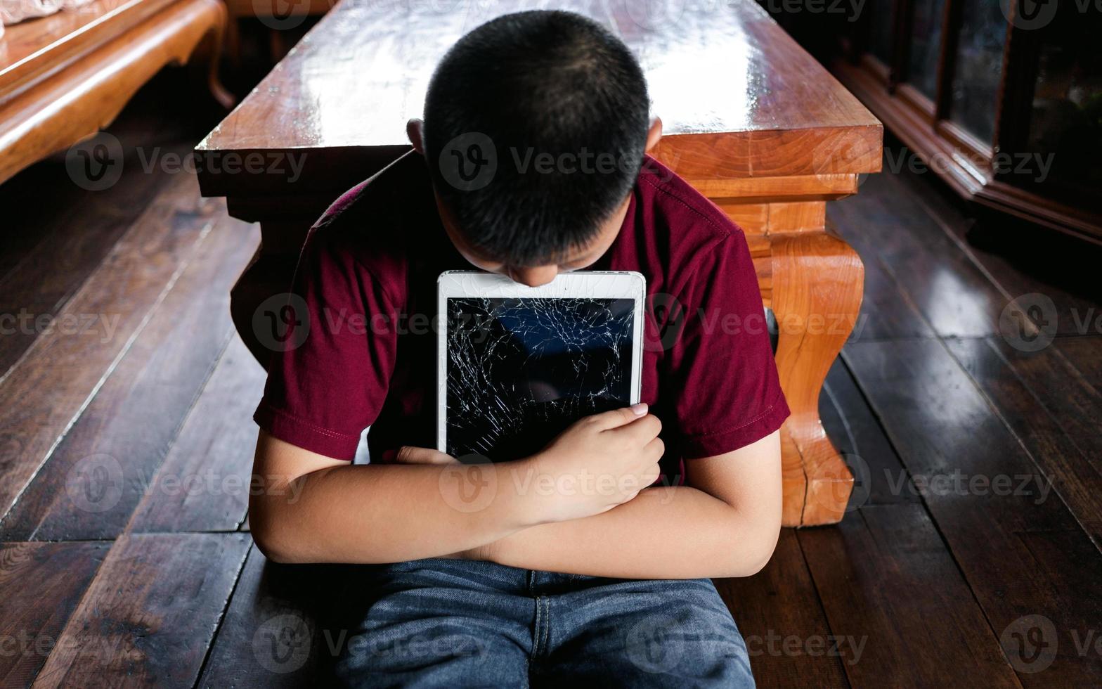 Portrait of a little Asian boy, Kid sad face, Unhappy child sitting hug broken tablet computer, Emotion sad and sad face, depressed children concept photo