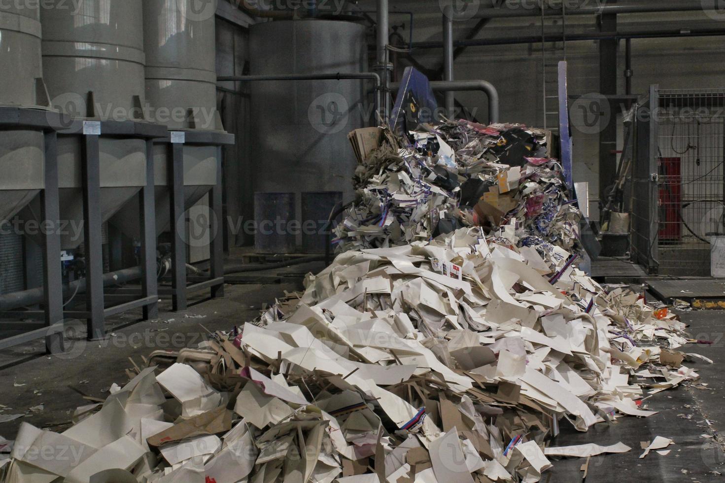 Shredding waste paper conveyor belt for recycling wrap, garbage and cardboard against bales of used carton boxes collected for reuse at industrial plant factory. Zero waste, eco-friendly concept photo