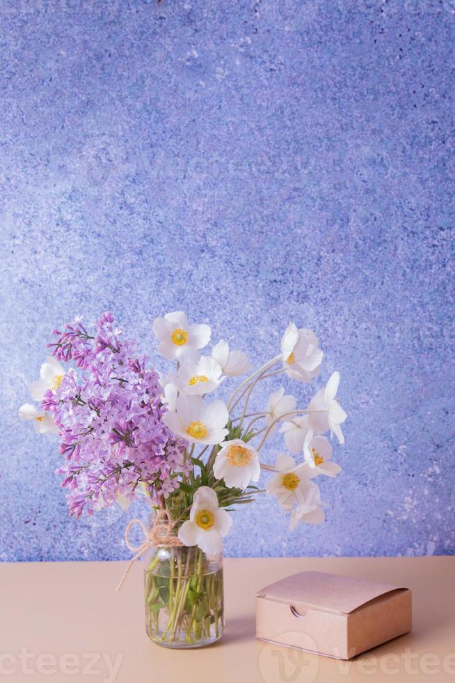 Ramo de flores lilas y anémonas con caja de regalo. concepto de saludo de primavera, día de la madre o 8 de marzo. foto