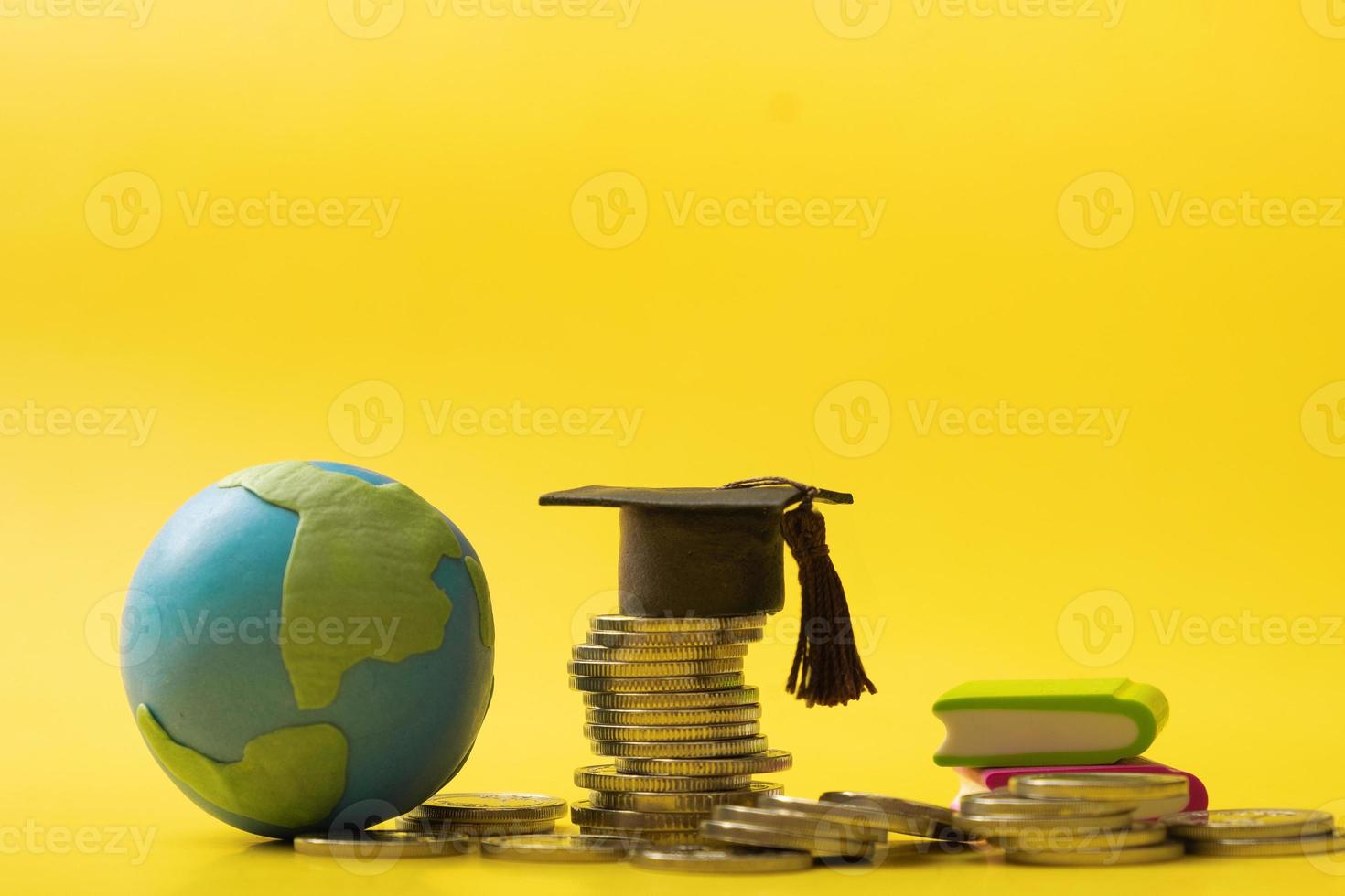 Graduated cap with coins and globe on yellow background. Savings for education concept photo