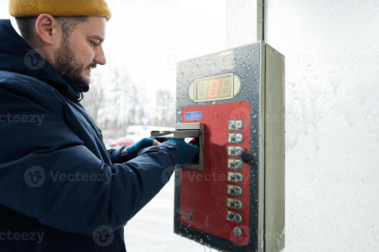 Man charges the device box with money at a self service wash in cold weather. photo