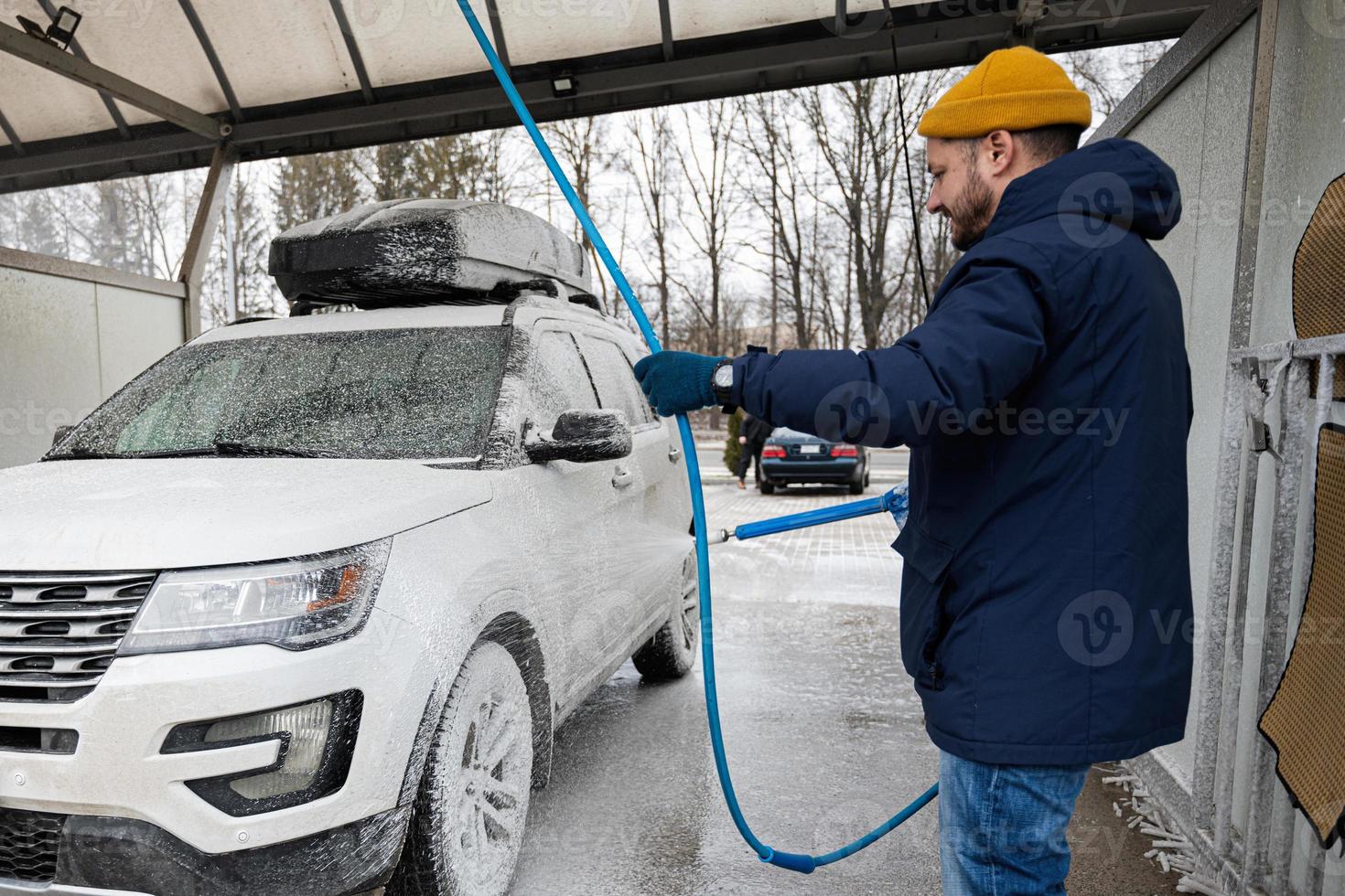 Man washing american SUV car with roof rack at a self service wash in cold weather. 18788707