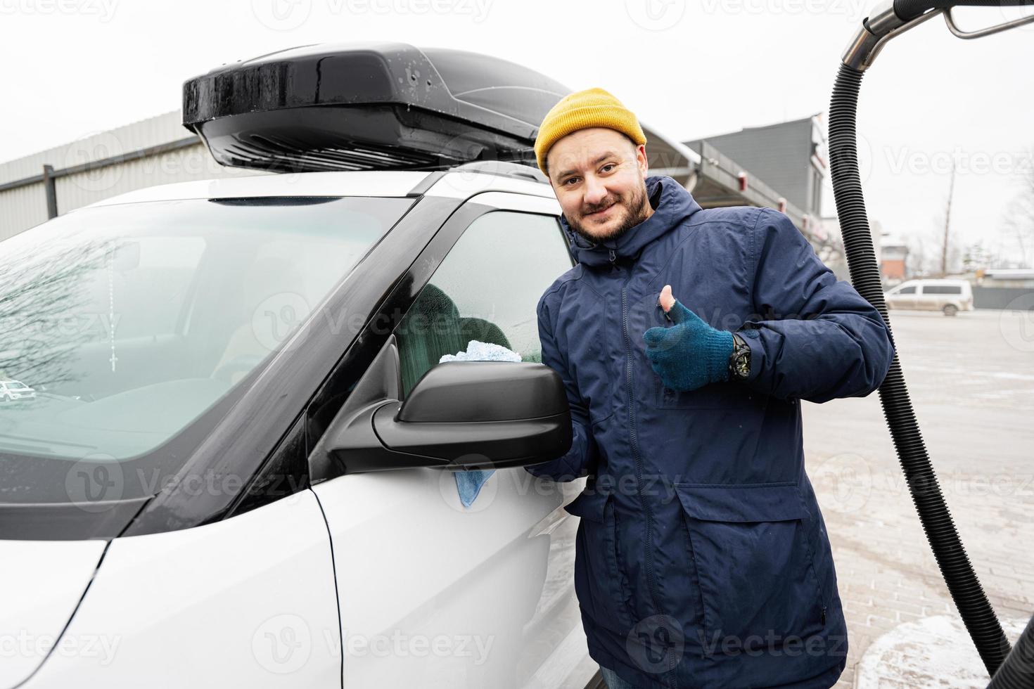 Man wipes american SUV car mirror with a microfiber cloth after washing in cold weather. photo