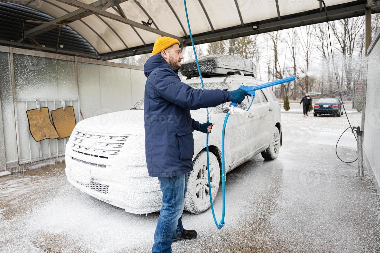 Man washing american SUV car with roof rack at a self service wash in