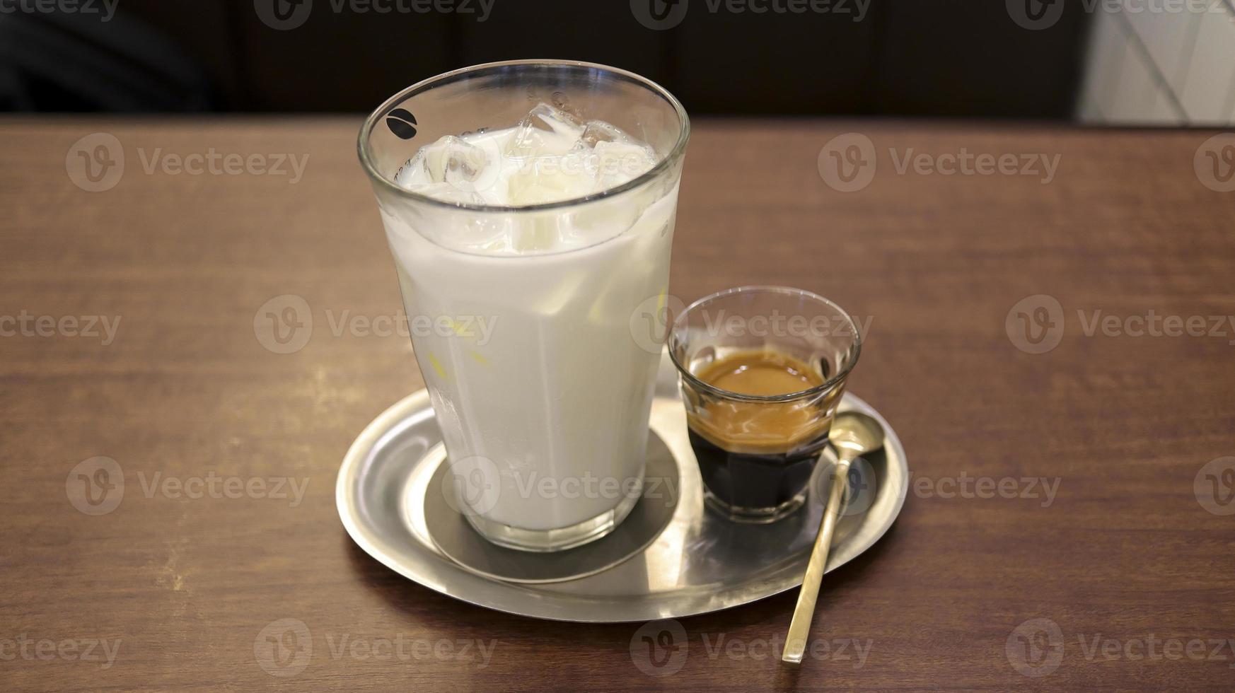 Separate a glass of milk and a small glass of espresso coffee for making cafe latte at the table. photo