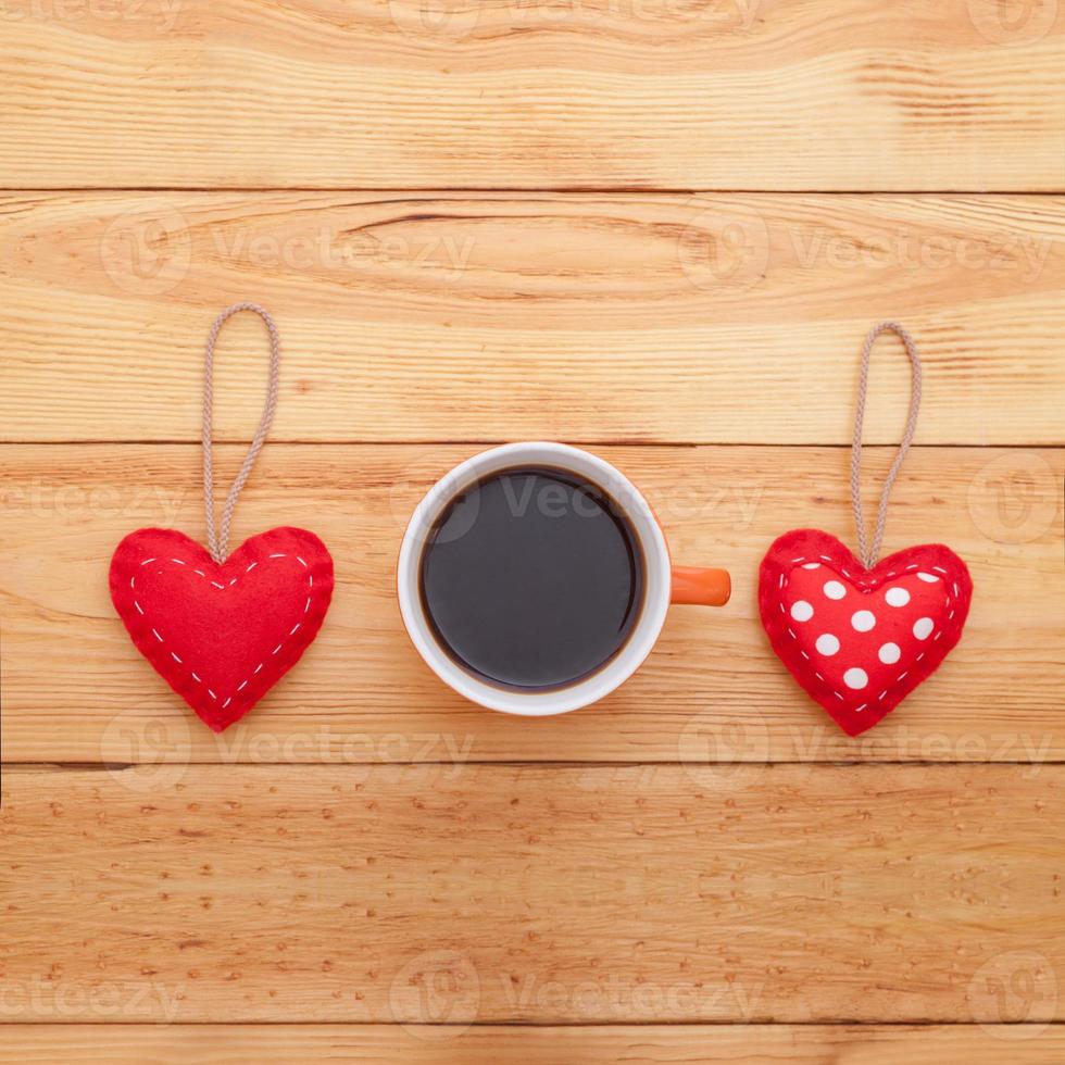 Cup of coffee and handmade heart fabric on wooden table photo