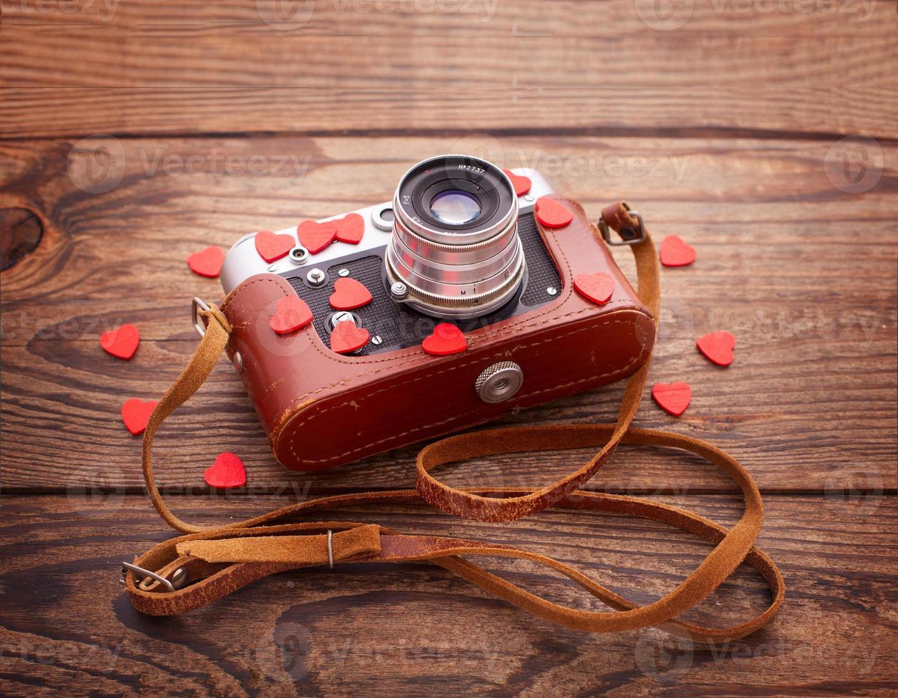 Retro Camera with red hearts on wooden background. photo