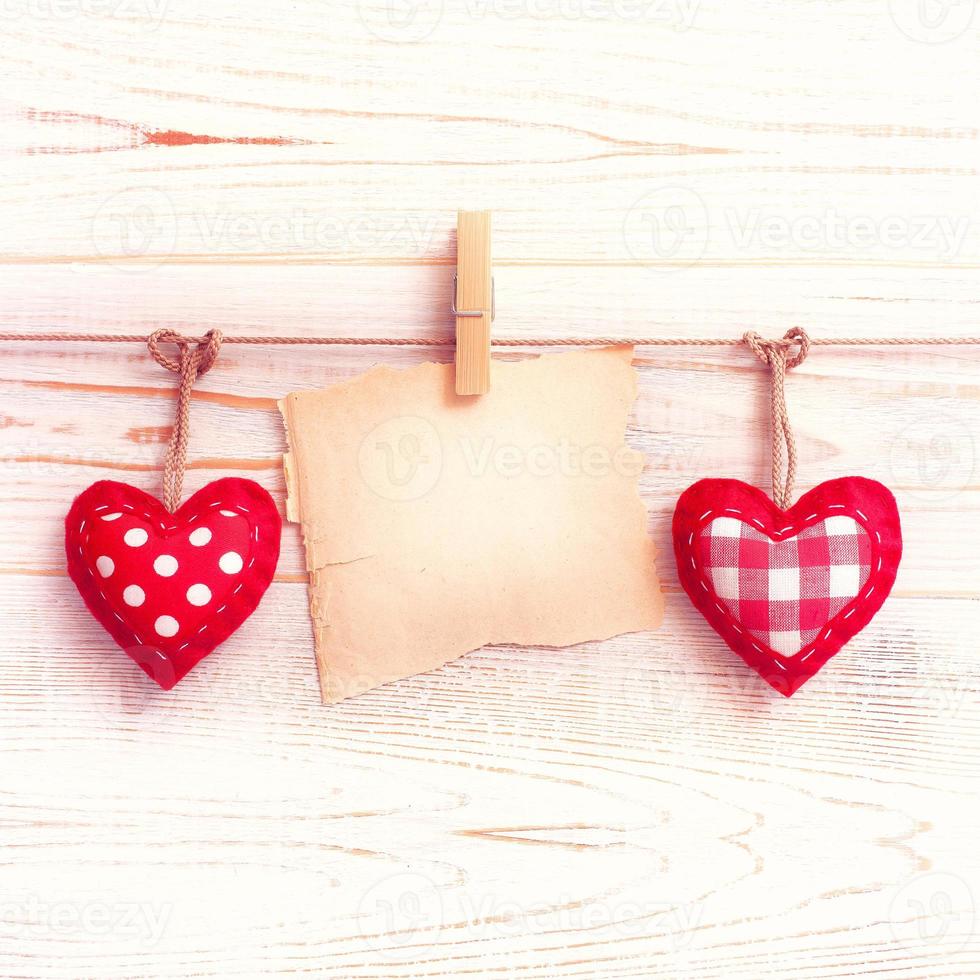 Blank sheet, a note, a torn sheet of paper and vintage red hearts hanging on garland. Valentines day concept photo