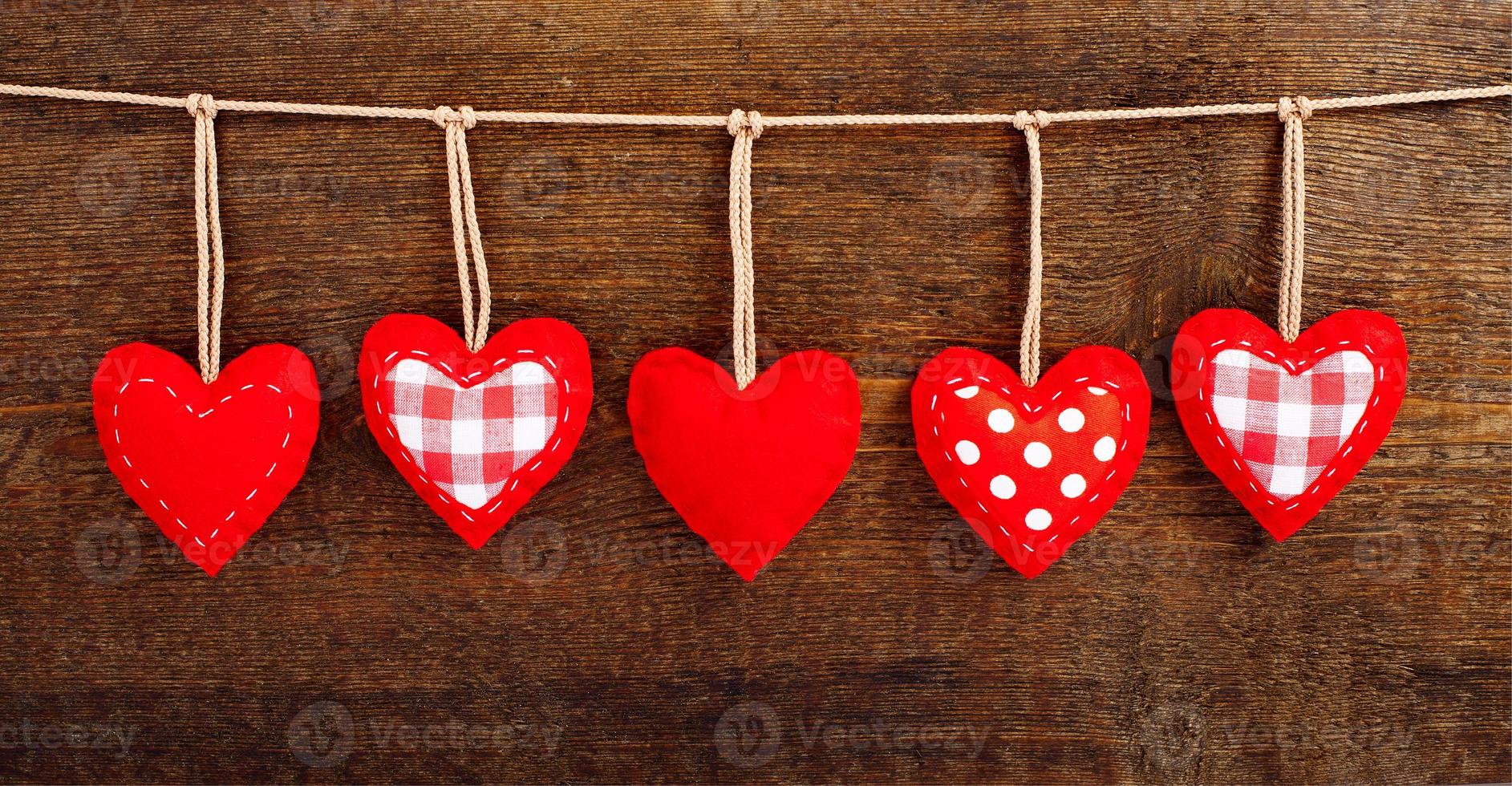 Vintage red hearts hanging on garland on wooden background. Valentines day concept photo