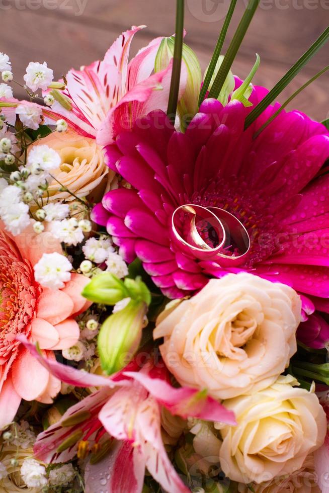 anillos de boda y muchas flores de colores con ramo de rosas foto