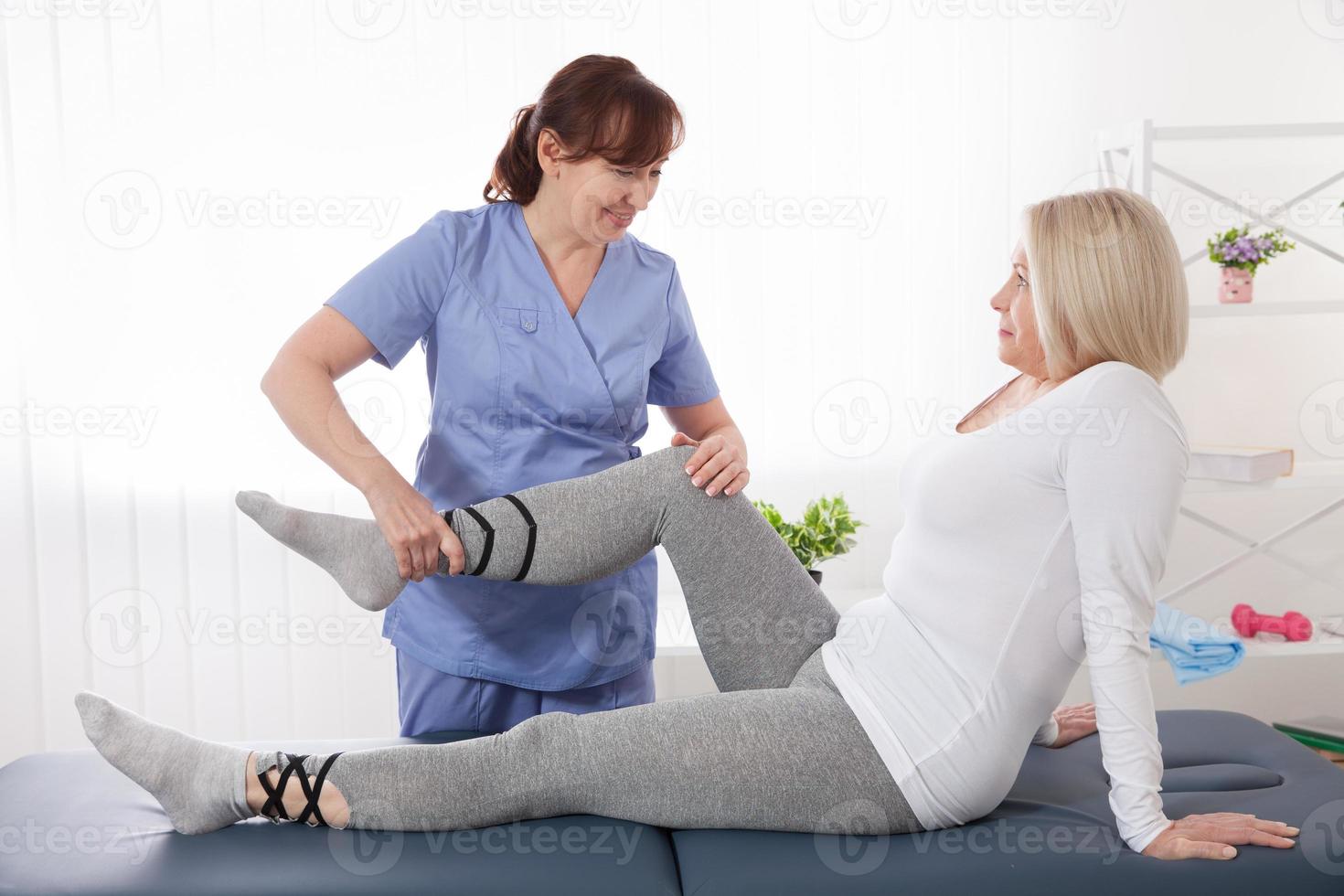 primer plano de la fisioterapeuta femenina masajeando la pierna del paciente en una sala de fisioterapia. foto