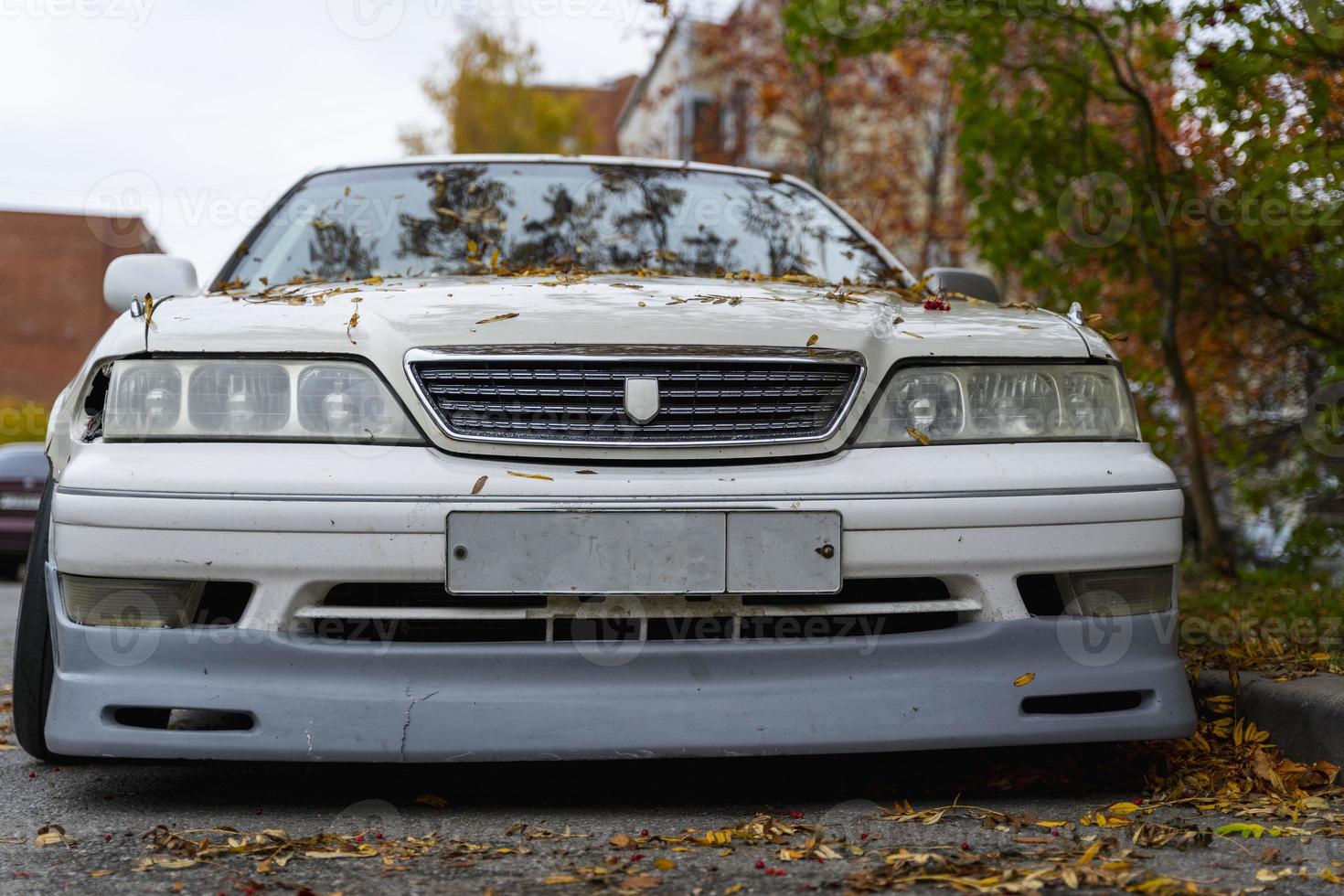 An old classic Japanese car in an autumn urban landscape, popular sedan made in Japan parking on city urban street photo