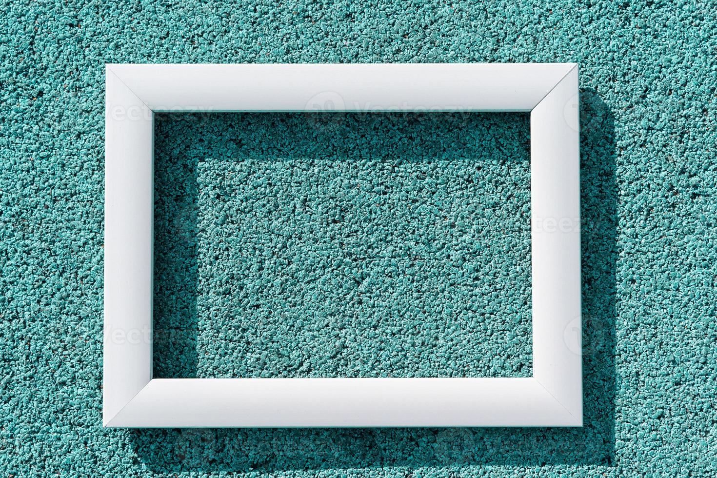 An empty white frame on a turquoise textured background, with a copy space. Minimal concept photo