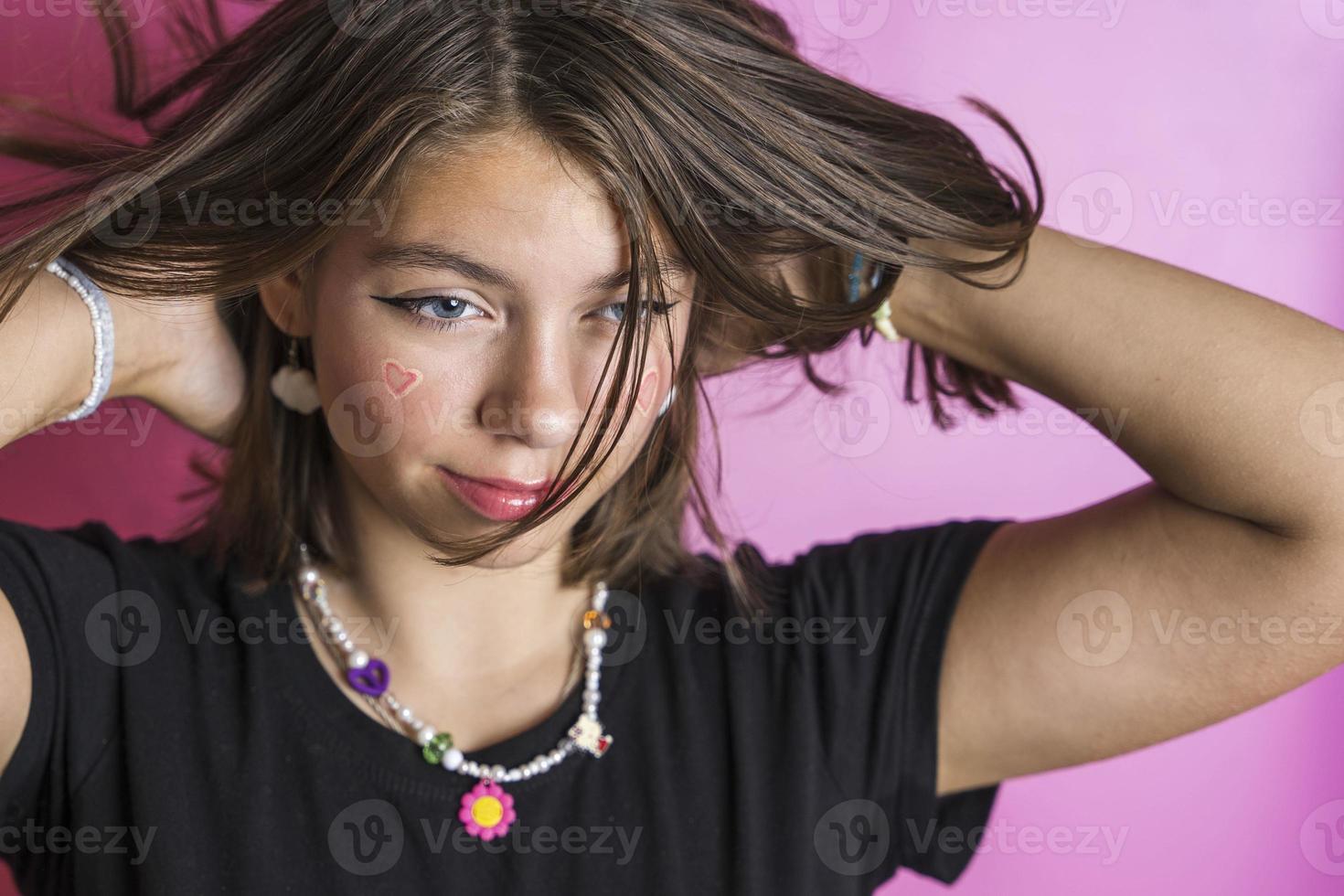 Portrait of a beautiful Caucasian girl shaking her hair, posing on a pink background photo