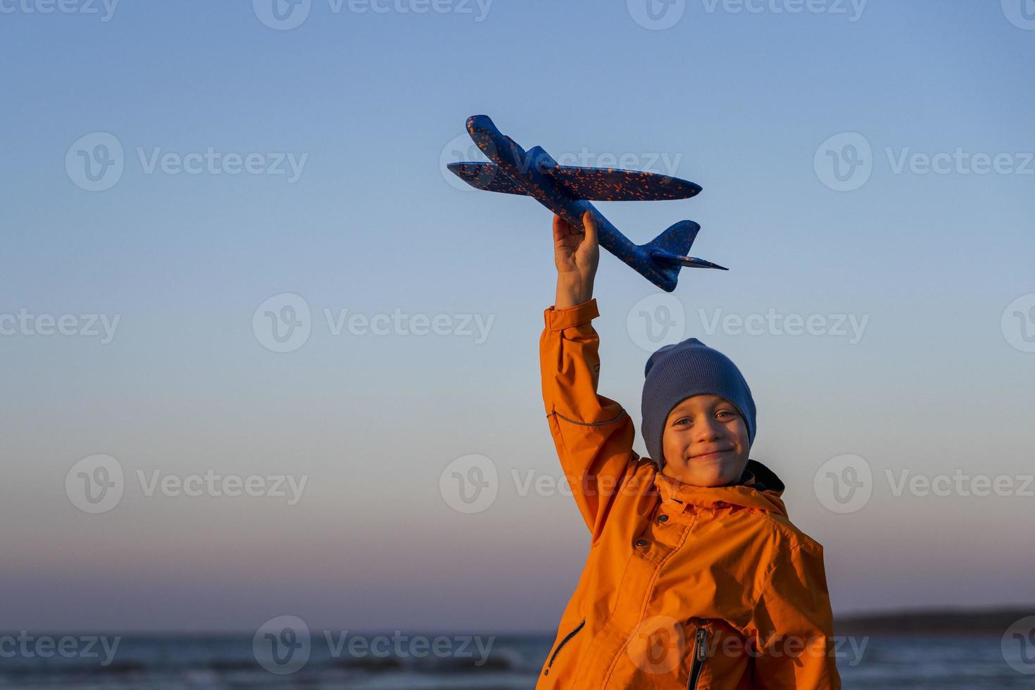 Portrait of a cute boy holding a plane in his hand against a blue sky, the path to a dream, the road to the sky photo