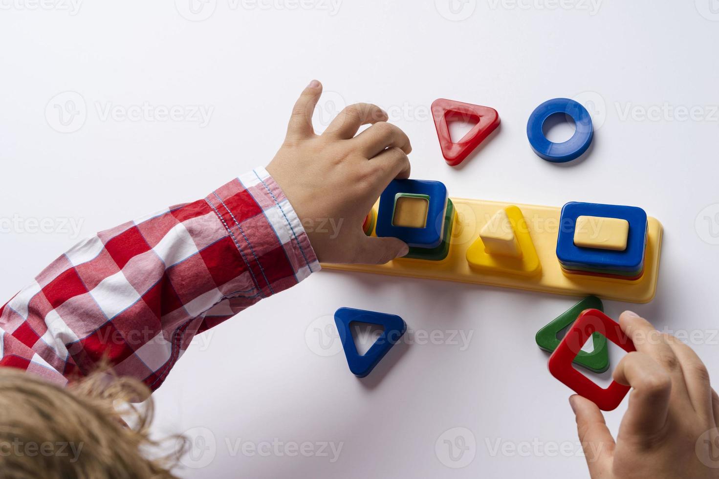 The child collects the sorter constructor. Puzzle sorter, an early development concept. Children's hands put the puzzle photo