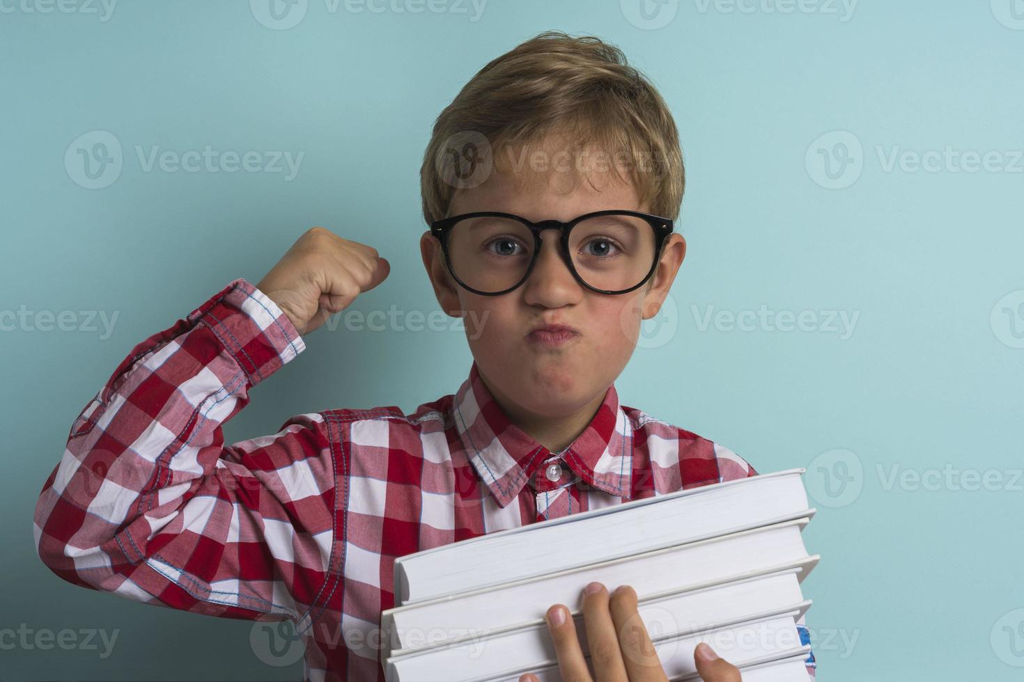 A boy with glasses, with books in his hands on a turquoise background. Knowledge is power, Back to school. photo