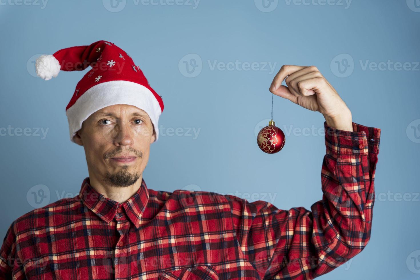 retrato de un hombre en una gorra de st. nicholas y una camisa roja a cuadros sobre un fondo azul foto