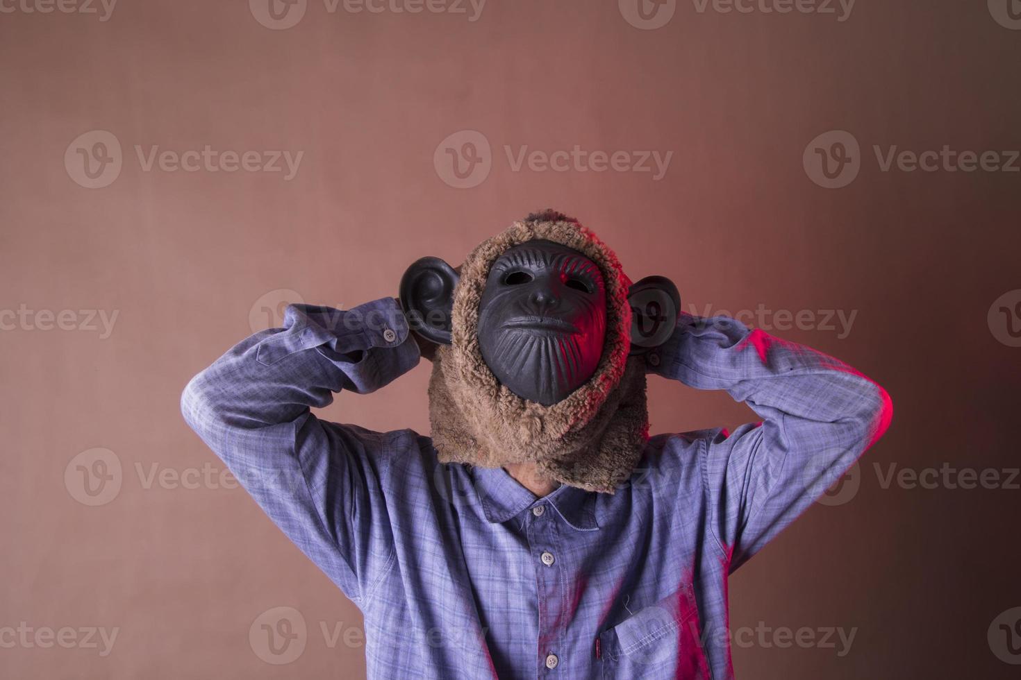 an annoyed old man in a monkey mask holding his head, photo