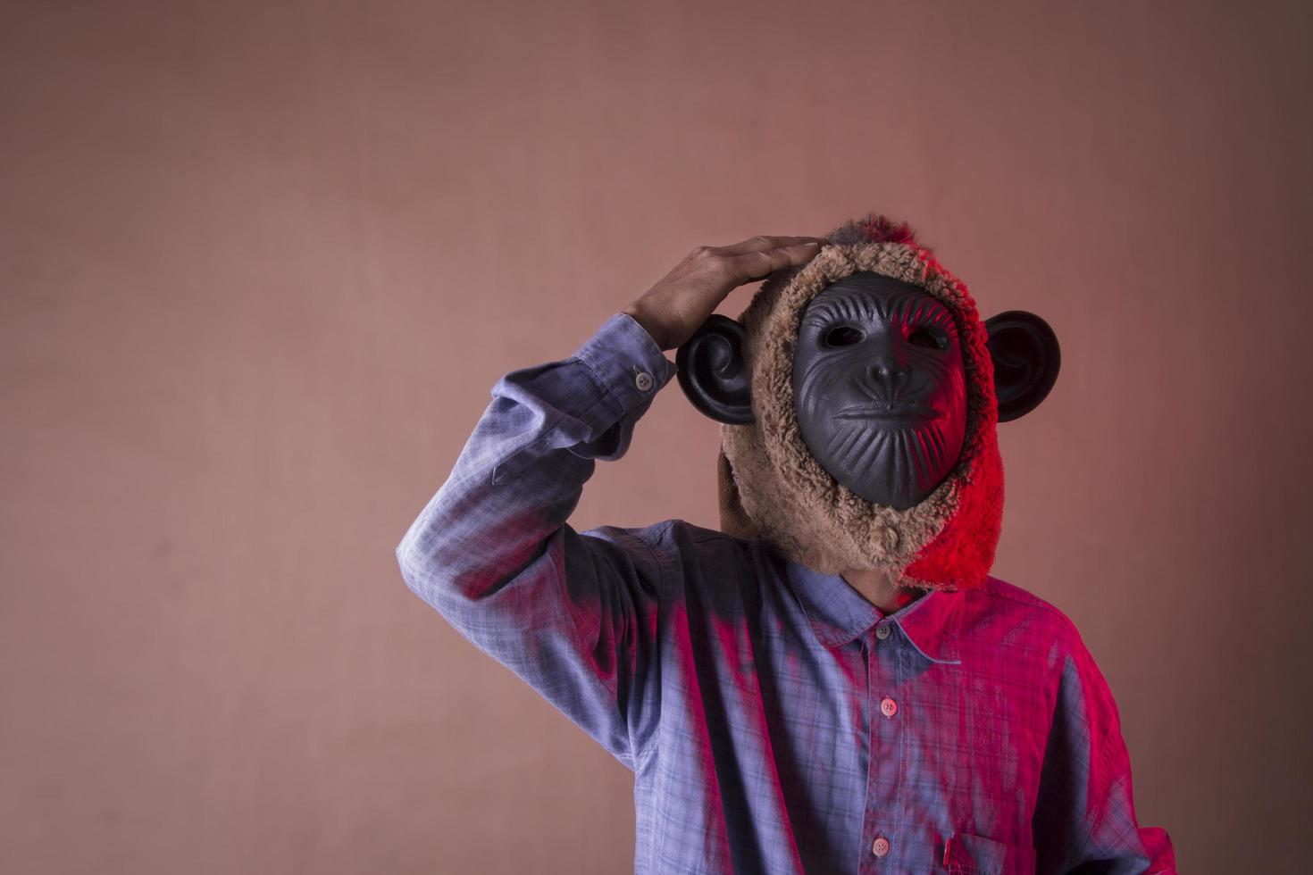 an annoyed old man in a monkey mask holding his head photo