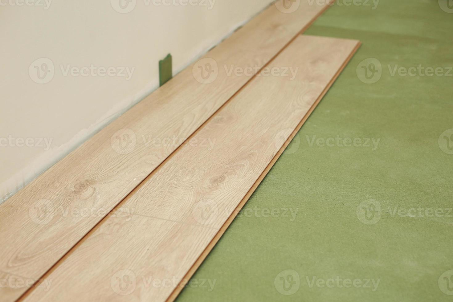 Installing wooden laminate or parquet floor in room over green base. assembling panels quickly and easily - affordable flooring. laying laminate flooring at home photo