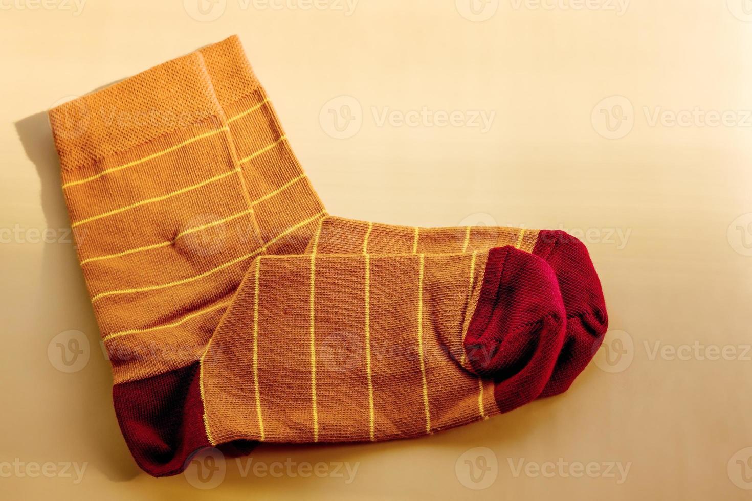 Brown socks with yellow stripes. New socks on a beige background. photo