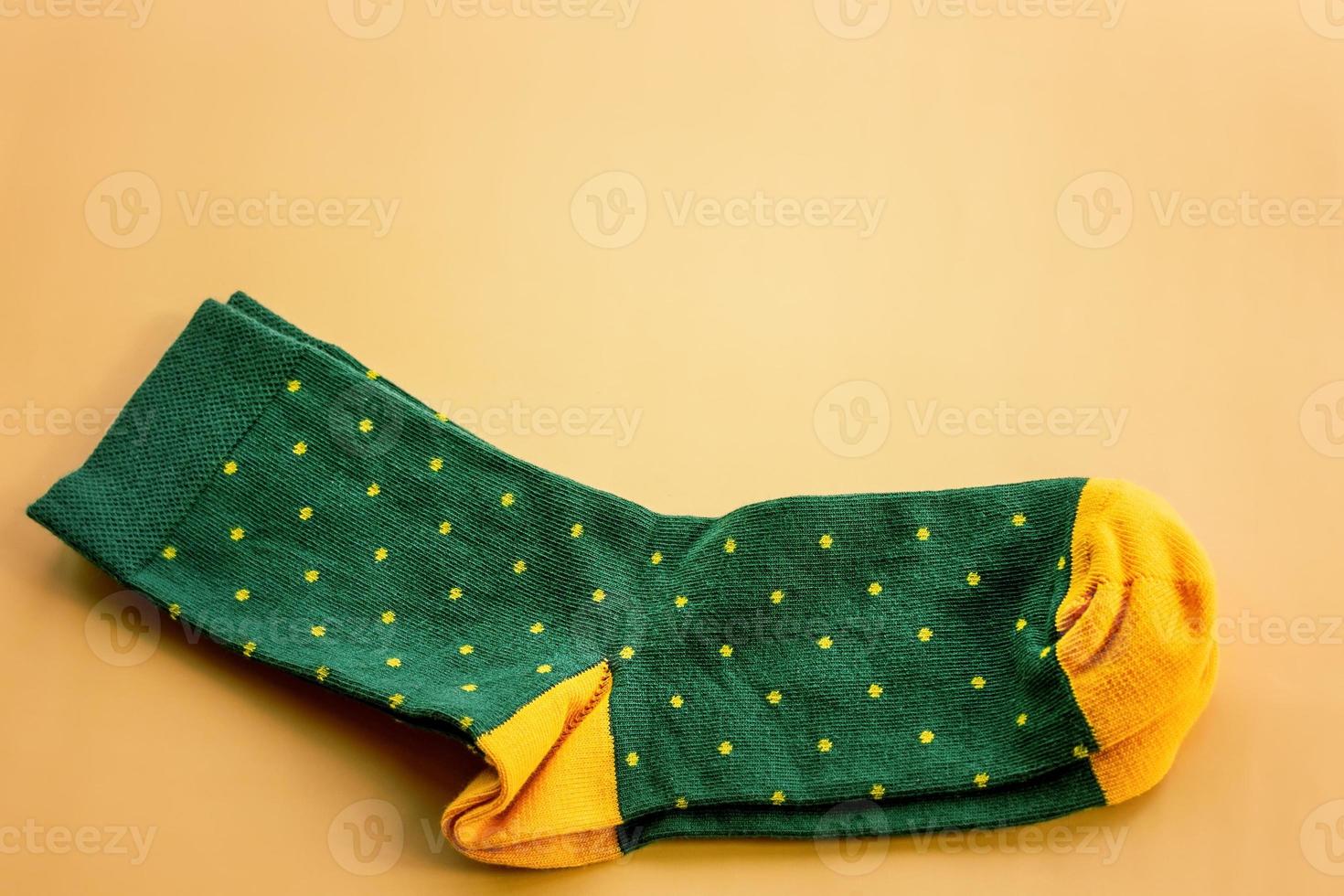 Green socks with yellow polka dots. A pair of socks on a beige background. photo