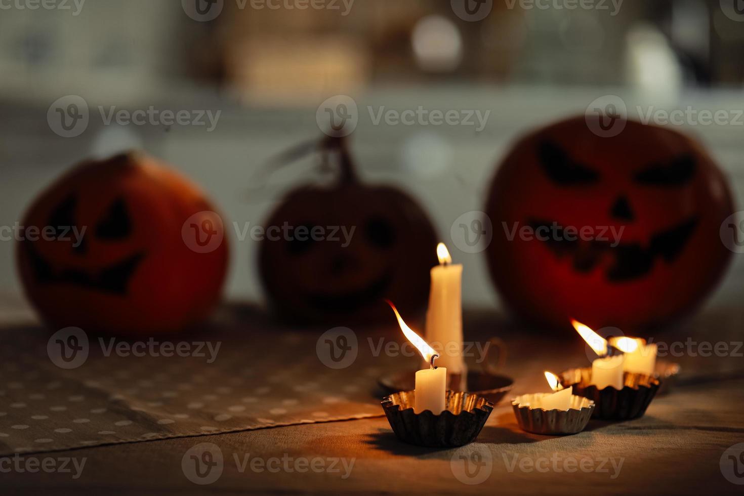 candles are burning on the table. Halloween pumpkin lantern with scary face on background. Family preparing all hallows eve Halloween party decorations. Background, copy space. selective focus photo