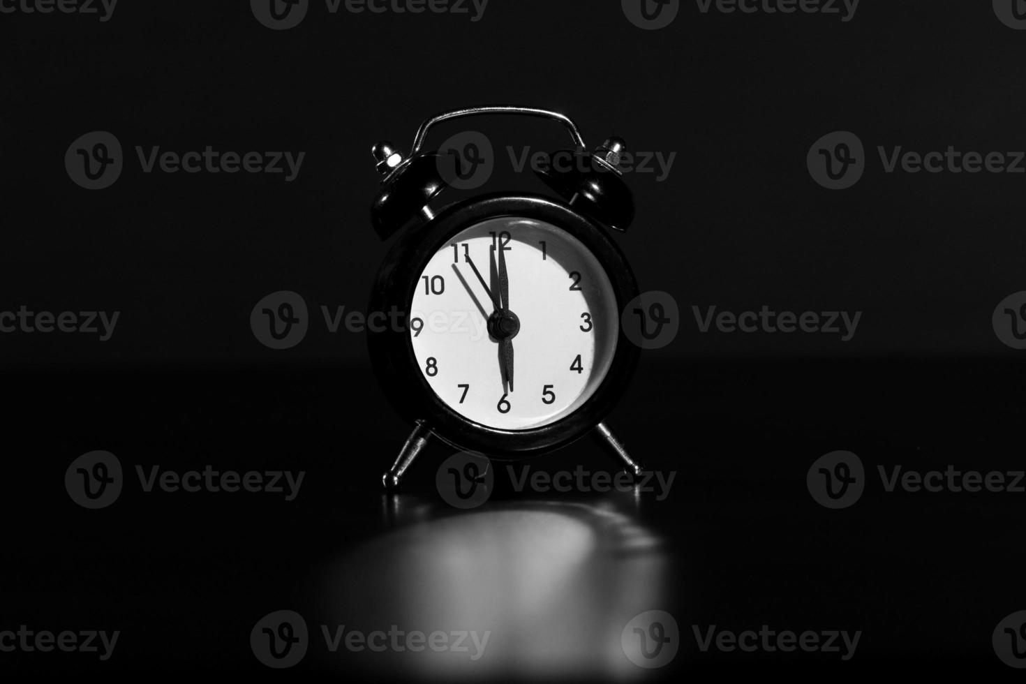 Black old style alarm clock isolated on black background. close-up photo