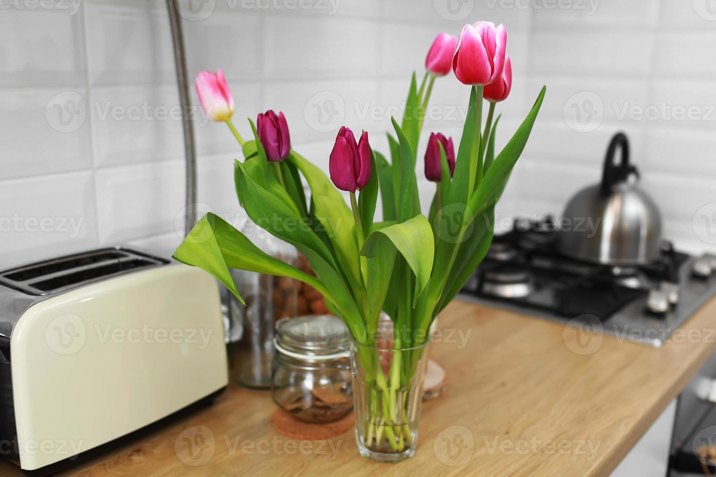 ramo de tulipanes en su casa sobre una encimera de madera en la cocina. foto