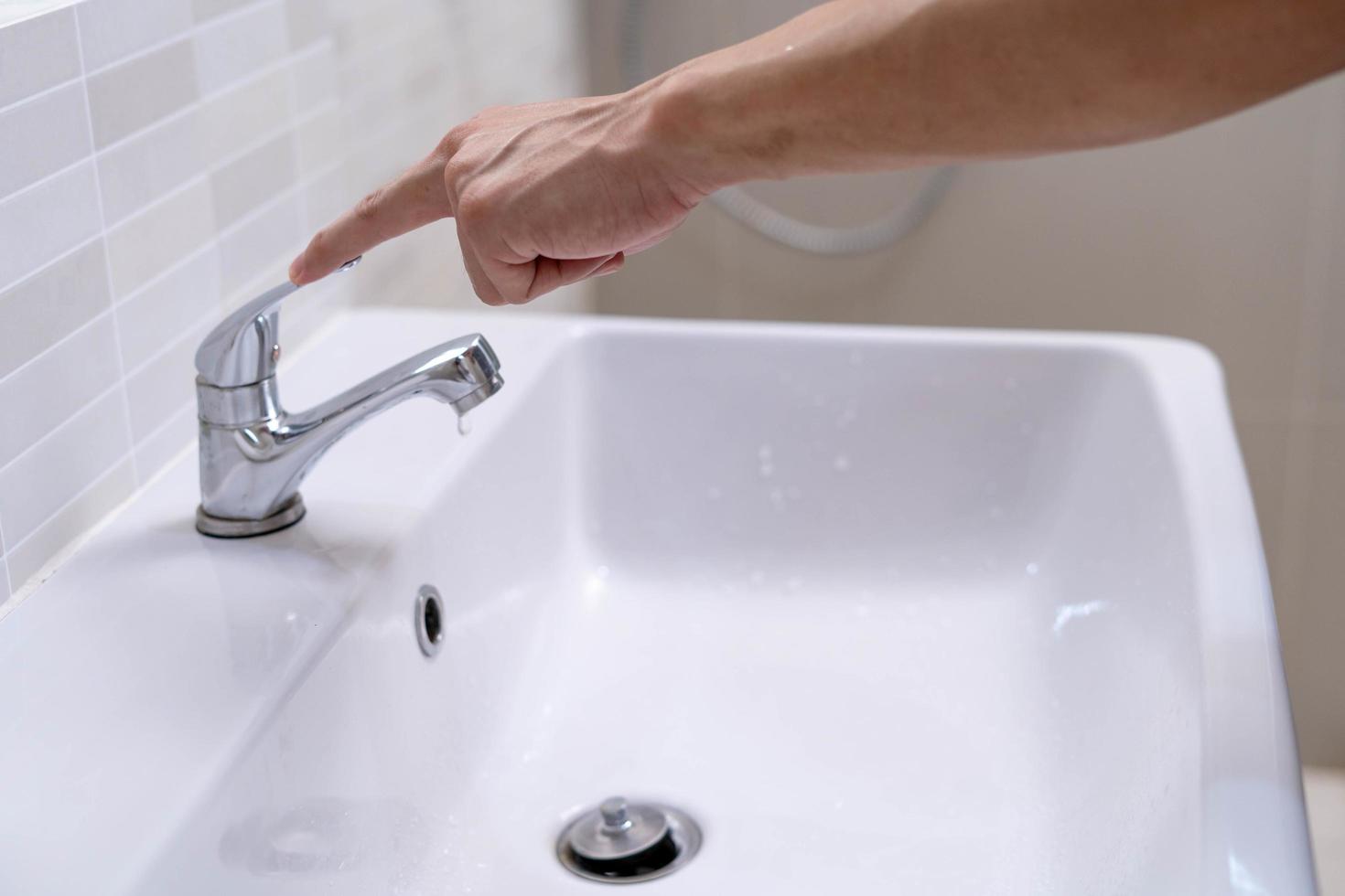 The faucet in the bathroom with running water. Man keeps turning off the water to save water energy and protect the environment. save water concept photo