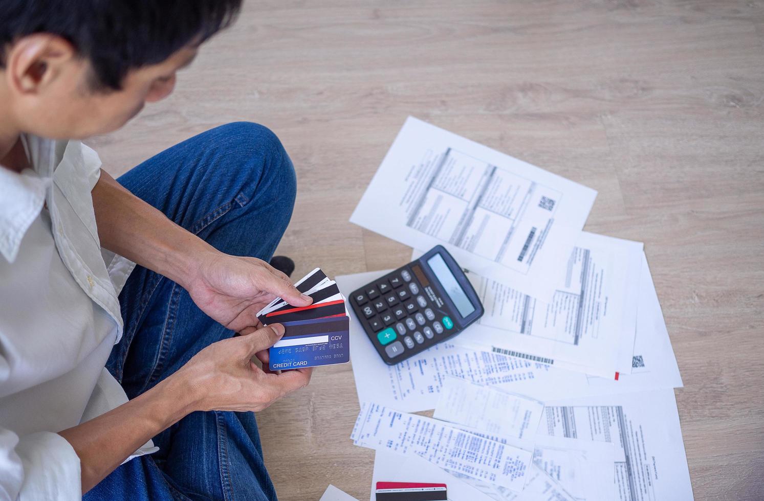 el hombre asiático está estresado por los problemas financieros. con facturas y varias facturas y calculadoras colocadas mientras tiene problemas con los gastos de la casa. concepto de deuda foto