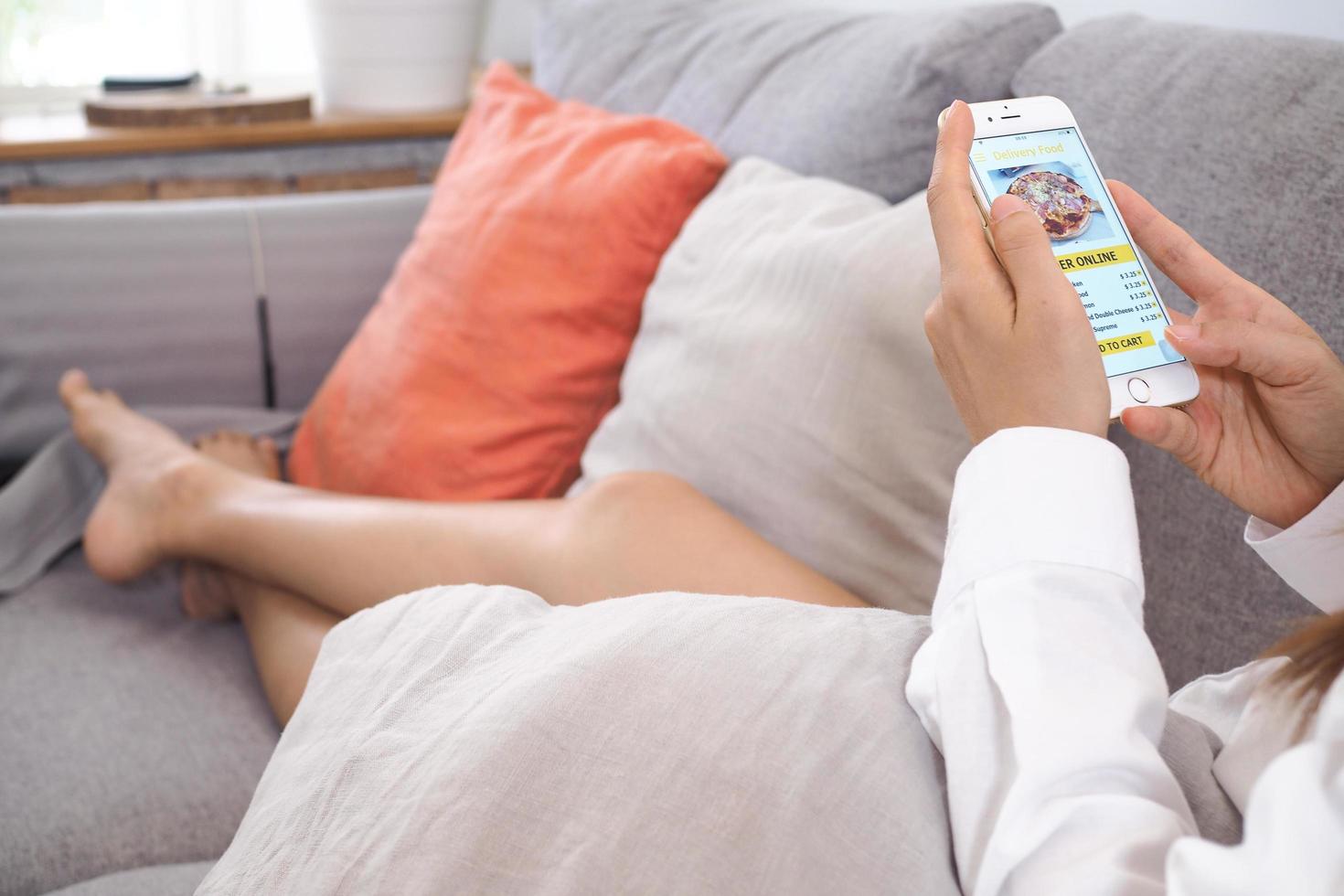 Woman sitting on the sofa inside the house Use a mobile phone to order food through the home delivery application. Choice of food delivery services do not go to the shop. photo