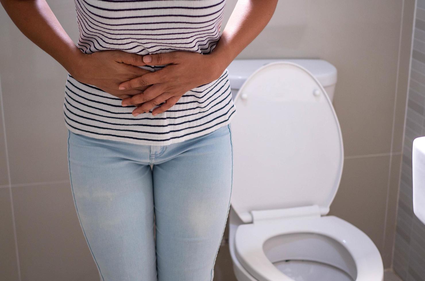 Women are standing in front of the bathroom door using their hands to hold the abdomen with severe abdominal pain or diarrhea. The concept of stomach cramps, diarrhea photo