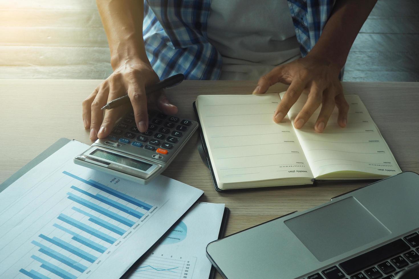 los hombres de negocios están usando una calculadora. Calcule el ingreso promedio de la empresa cada mes. tienen gráficos y datos estadísticos. foto