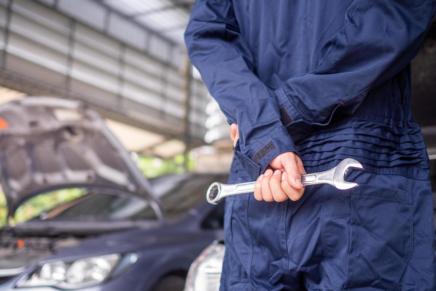 The mechanic wears a uniform and has a screwdriver. Concept of car service, repair, maintenance, ready to service photo